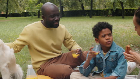 African-American-Man-Petting-Dog-and-Talking-with-Family-on-Picnic